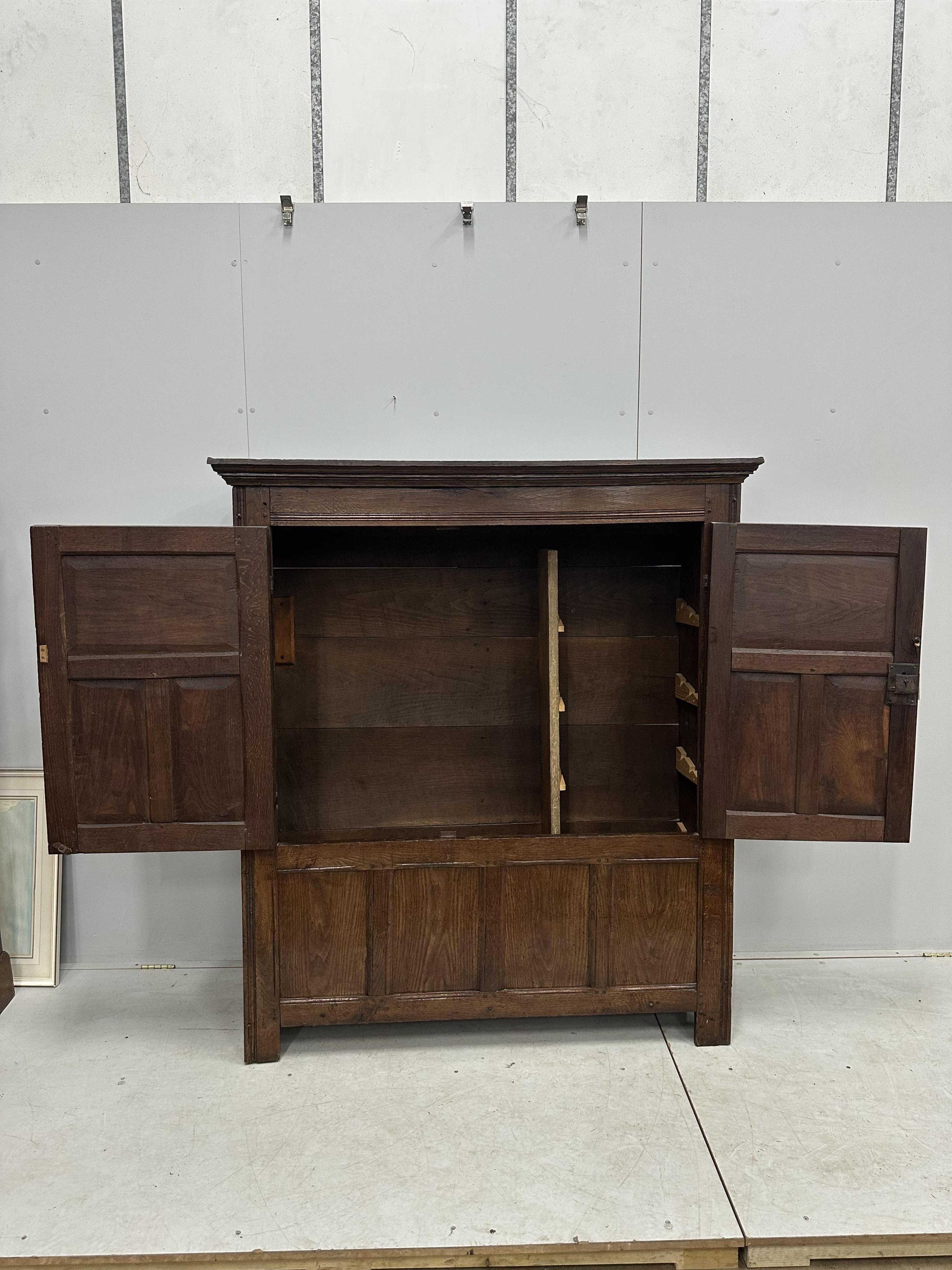 An 18th century and later panelled oak cupboard, width 140cm, height 159cm. Condition - good